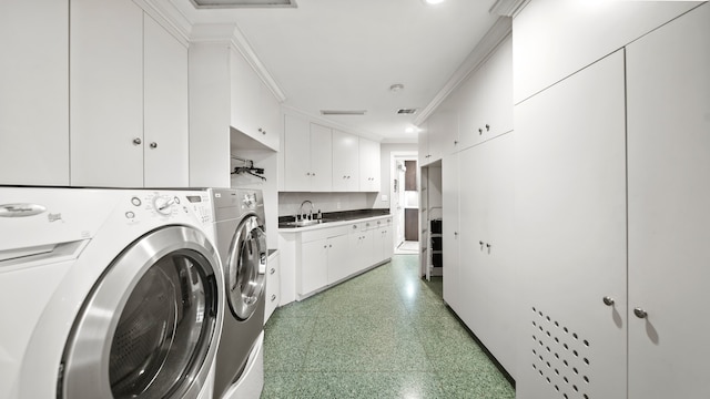 washroom with ornamental molding, cabinets, sink, and washer and dryer