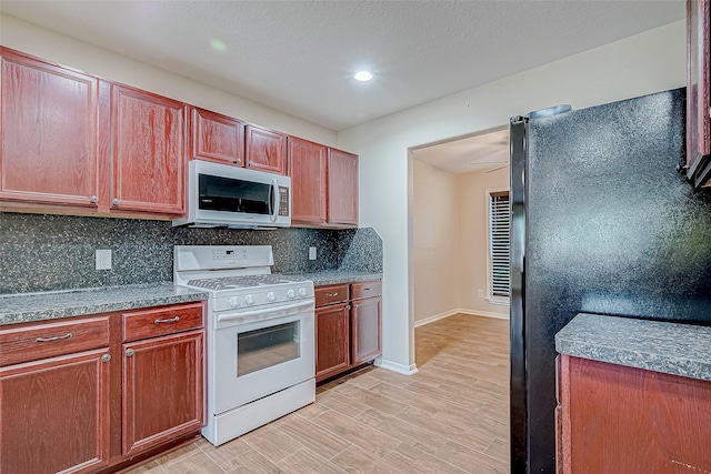 kitchen with white range oven, tasteful backsplash, and light wood-type flooring