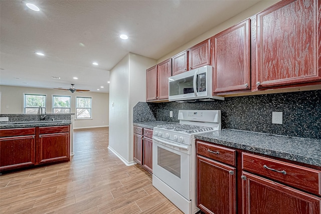 kitchen featuring sink, ceiling fan, light wood-type flooring, tasteful backsplash, and white range with gas stovetop