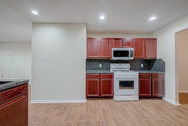 kitchen with decorative backsplash, white range oven, a textured ceiling, and light hardwood / wood-style flooring