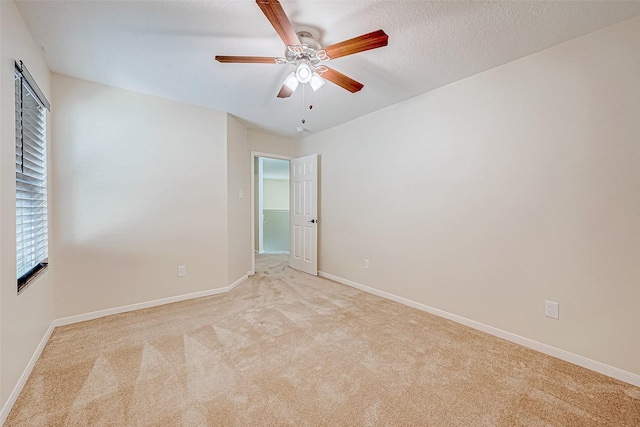 spare room featuring light carpet, ceiling fan, and a textured ceiling