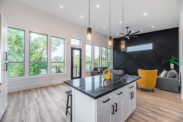 kitchen with white cabinetry, a kitchen breakfast bar, plenty of natural light, and a center island