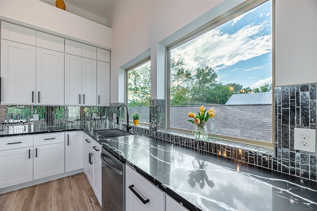 kitchen featuring dishwasher, white cabinets, sink, backsplash, and light hardwood / wood-style flooring