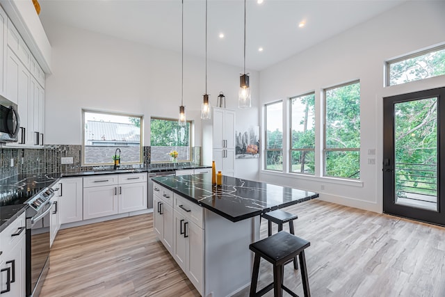 kitchen featuring light hardwood / wood-style floors, tasteful backsplash, a kitchen bar, a center island, and white cabinets