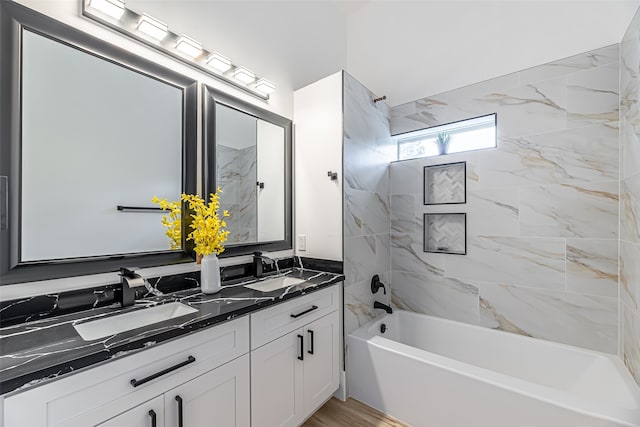 bathroom featuring hardwood / wood-style floors, vanity, tiled shower / bath combo, and tasteful backsplash