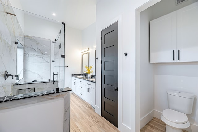 bathroom featuring a tile shower, vanity, hardwood / wood-style flooring, and toilet