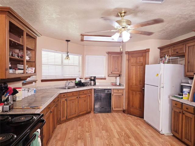 kitchen featuring black appliances, hanging light fixtures, a textured ceiling, and light hardwood / wood-style flooring