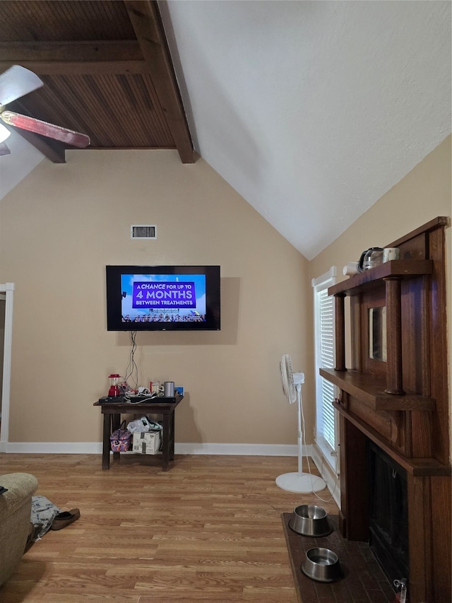 living room with light hardwood / wood-style flooring, vaulted ceiling with beams, and ceiling fan