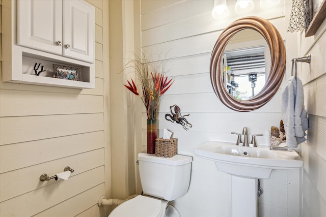 bathroom featuring wood walls and toilet