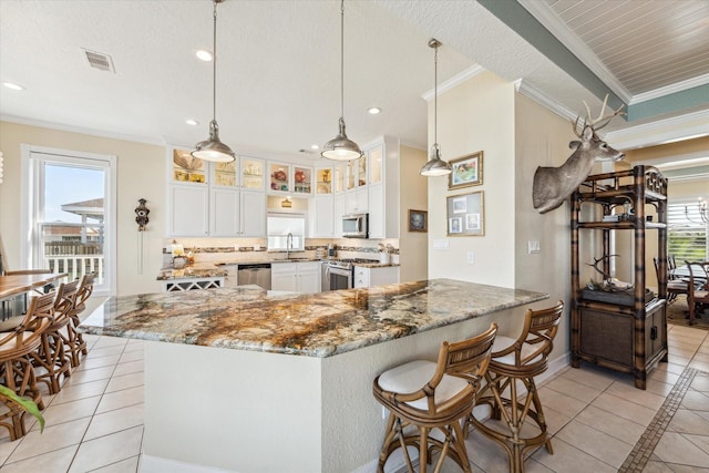 kitchen featuring crown molding, decorative light fixtures, white cabinets, and appliances with stainless steel finishes