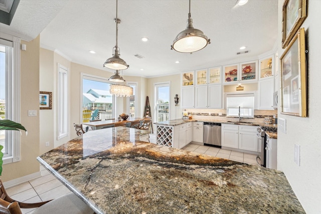 kitchen featuring sink, light tile patterned floors, white cabinetry, stainless steel appliances, and decorative light fixtures