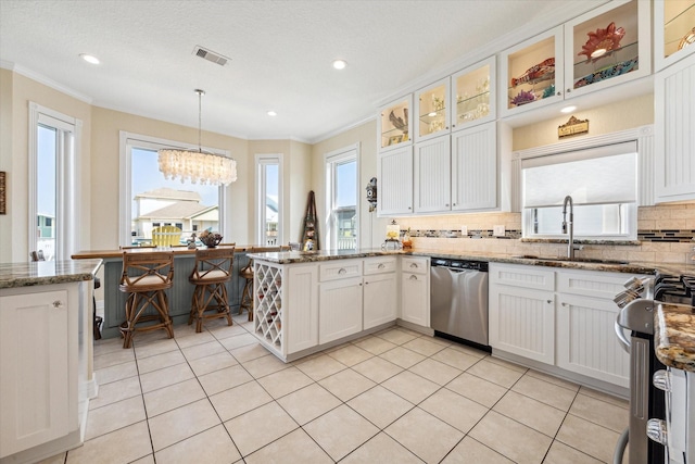 kitchen featuring white cabinetry, sink, stainless steel dishwasher, and decorative light fixtures