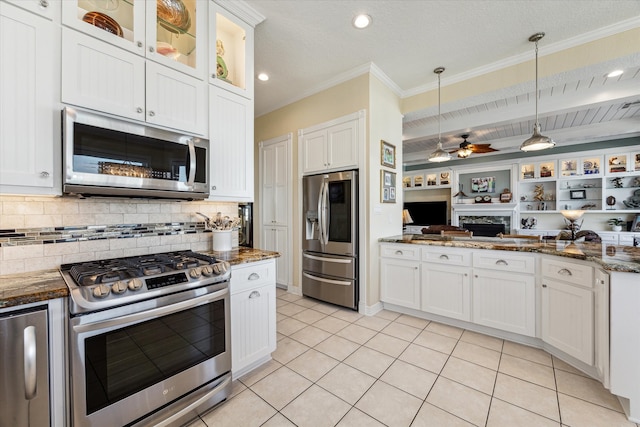 kitchen featuring stainless steel appliances, dark stone counters, light tile patterned flooring, white cabinetry, and decorative light fixtures