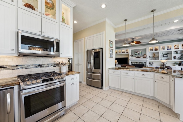 kitchen with white cabinetry, decorative light fixtures, light tile patterned floors, dark stone countertops, and stainless steel appliances