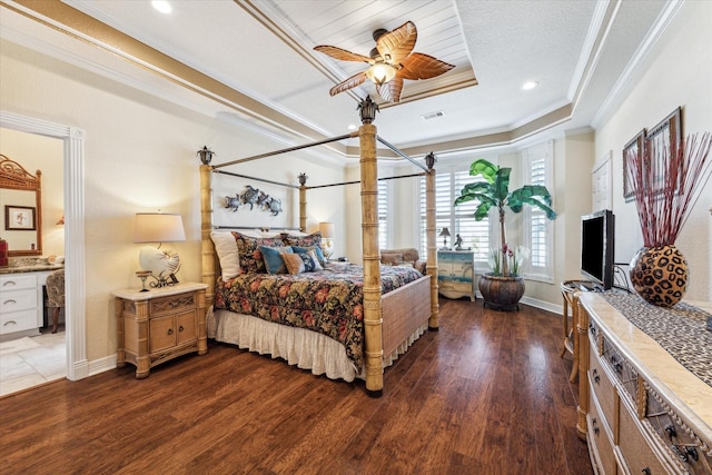 bedroom with crown molding, a tray ceiling, dark hardwood / wood-style flooring, and ensuite bath