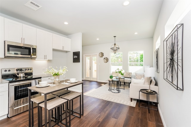 kitchen with white cabinets, appliances with stainless steel finishes, decorative light fixtures, and dark hardwood / wood-style flooring