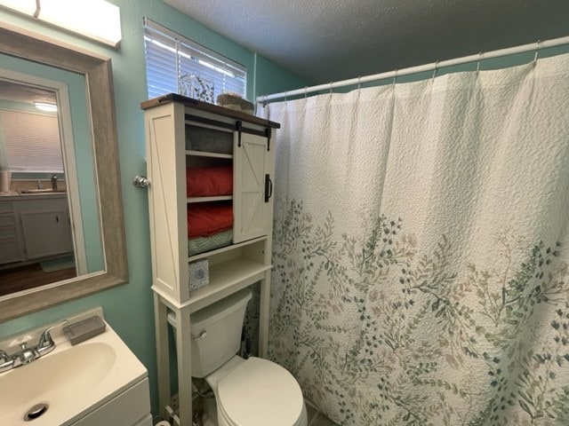 bathroom with toilet, a shower with curtain, vanity, and a textured ceiling