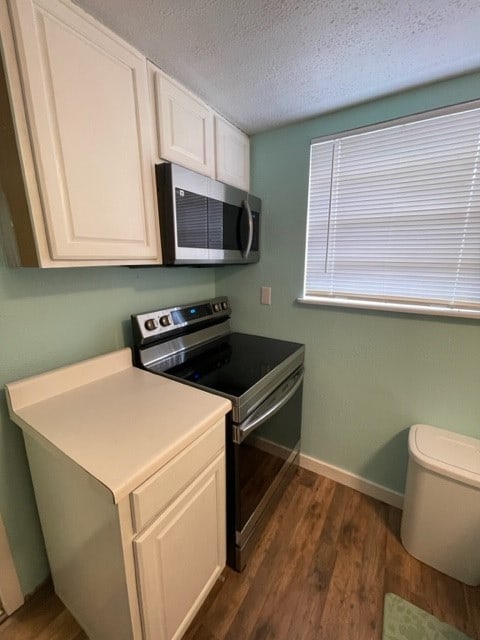 kitchen featuring dark hardwood / wood-style flooring, white cabinets, a textured ceiling, and stainless steel appliances