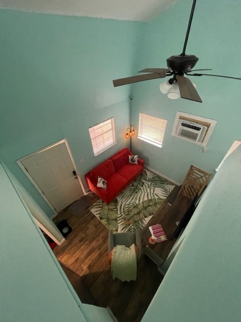 living room featuring a wall mounted AC, hardwood / wood-style floors, vaulted ceiling, and ceiling fan