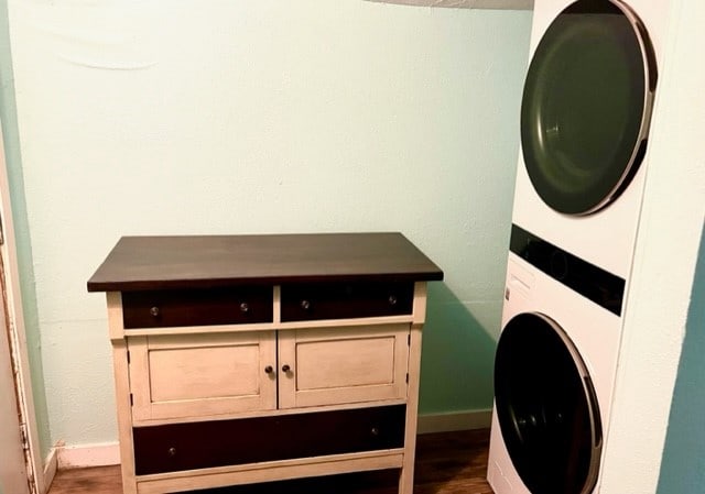 washroom featuring wood-type flooring and stacked washer / drying machine