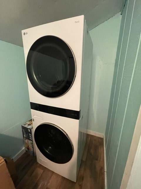 clothes washing area with stacked washing maching and dryer and dark hardwood / wood-style floors