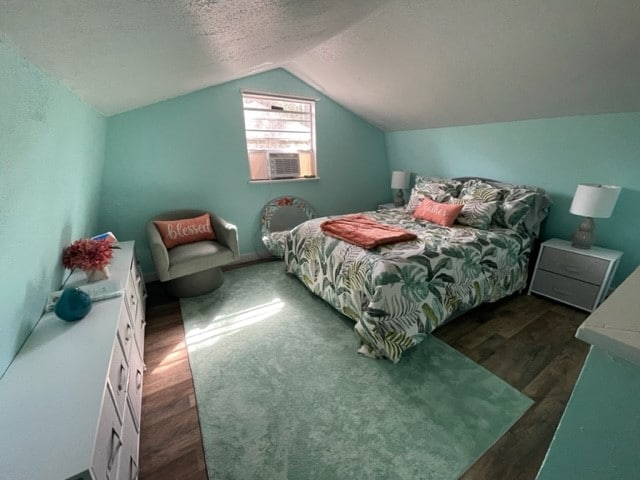 bedroom with cooling unit, dark hardwood / wood-style flooring, lofted ceiling, and a textured ceiling