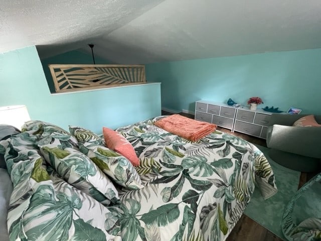 bedroom featuring a textured ceiling and vaulted ceiling