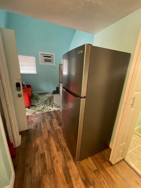 kitchen with a wall unit AC, wood-type flooring, and stainless steel fridge