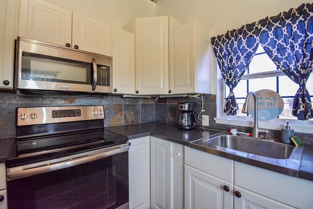 7120 E Hunter Dr, Hitchcock, TX 77563 - kitchen with appliances with stainless steel finishes, a sink, white cabinets, dark countertops, and tasteful backsplash