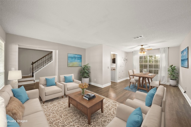 living room featuring wood-type flooring, ceiling fan, and a textured ceiling