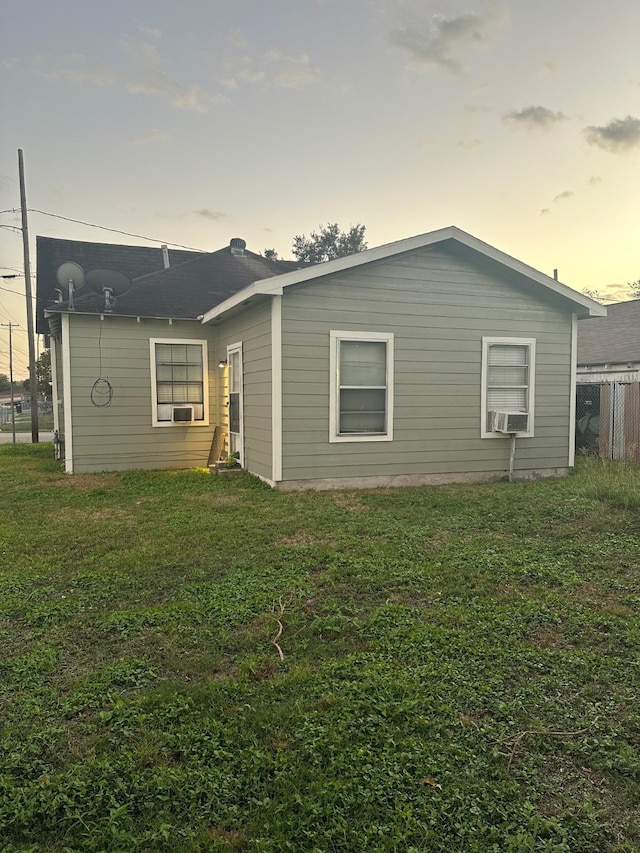 back house at dusk featuring a lawn and cooling unit