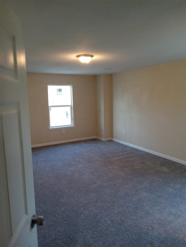 unfurnished room with dark carpet