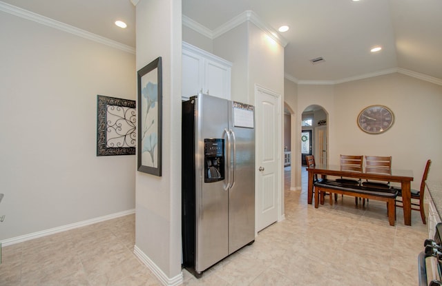 kitchen featuring lofted ceiling, white cabinets, light tile patterned floors, crown molding, and stainless steel fridge