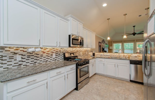 kitchen with appliances with stainless steel finishes, decorative backsplash, sink, vaulted ceiling, and white cabinets