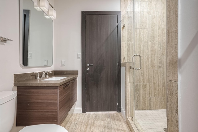 bathroom featuring vanity, a shower with shower door, and toilet