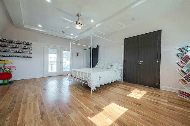 unfurnished bedroom with a raised ceiling, light hardwood / wood-style flooring, ceiling fan, and french doors