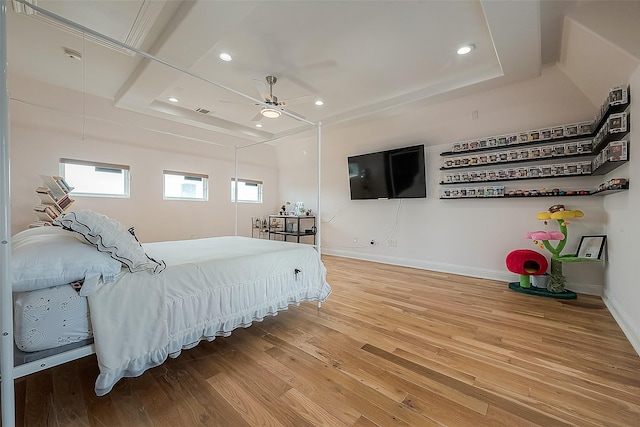 bedroom featuring hardwood / wood-style floors, a tray ceiling, and ceiling fan