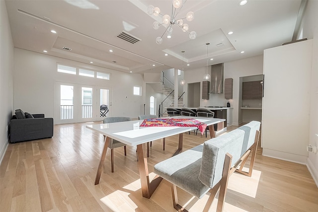 dining room featuring a raised ceiling, a notable chandelier, and light hardwood / wood-style floors