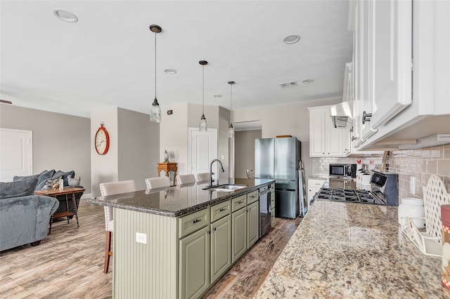 kitchen featuring stainless steel appliances, sink, a kitchen breakfast bar, dark stone counters, and a kitchen island with sink