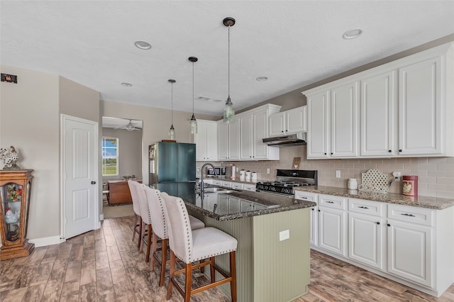 kitchen featuring white cabinetry, an island with sink, and stainless steel fridge