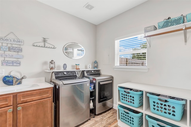 laundry area featuring washer and clothes dryer, light wood-type flooring, and cabinets