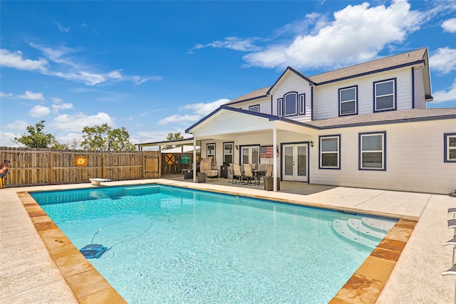 view of swimming pool featuring a diving board, a patio, and french doors