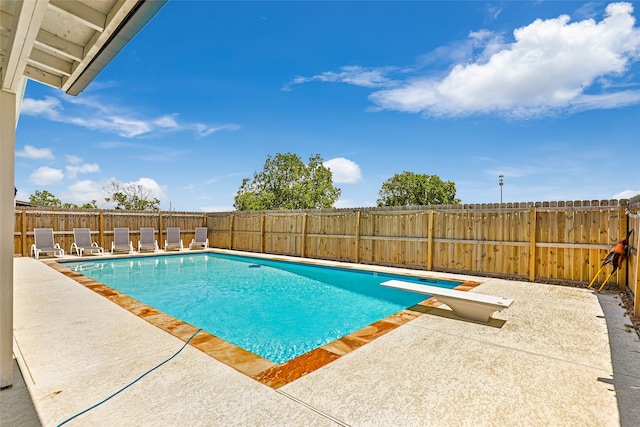 view of pool with a patio area and a diving board