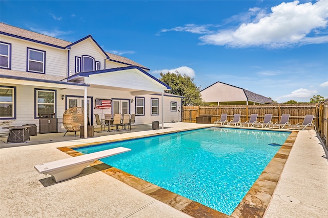 view of pool with a diving board and a patio