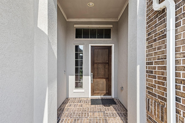 view of exterior entry with brick siding and stucco siding