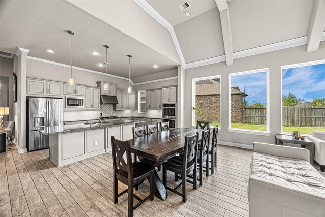 dining area with light wood-type flooring, visible vents, and crown molding