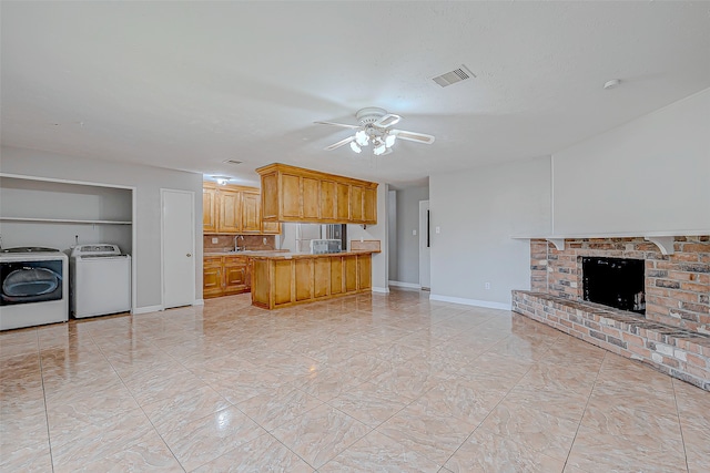 kitchen with built in features, a fireplace, kitchen peninsula, independent washer and dryer, and ceiling fan