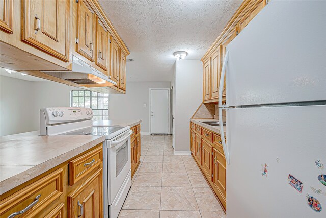 kitchen with a textured ceiling, white appliances, and light tile patterned flooring