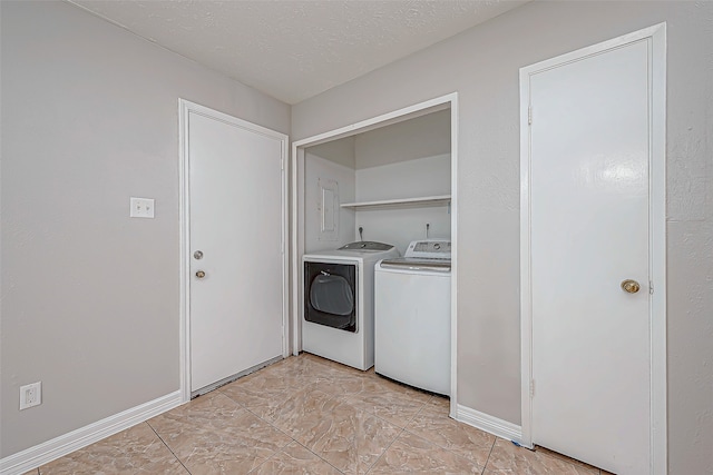 washroom with light tile patterned flooring, a textured ceiling, and washer and clothes dryer