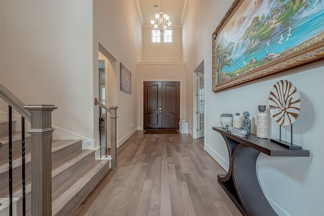 entrance foyer featuring light hardwood / wood-style floors, a notable chandelier, and a high ceiling